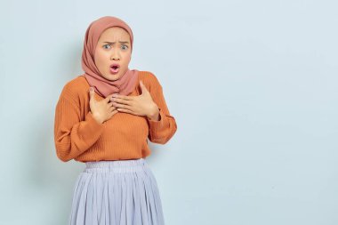 Kahverengi süveter ve tesettürlü, göğsünde beyaz arka planda izole bir el olan Asyalı güzel bir kadının portresi.