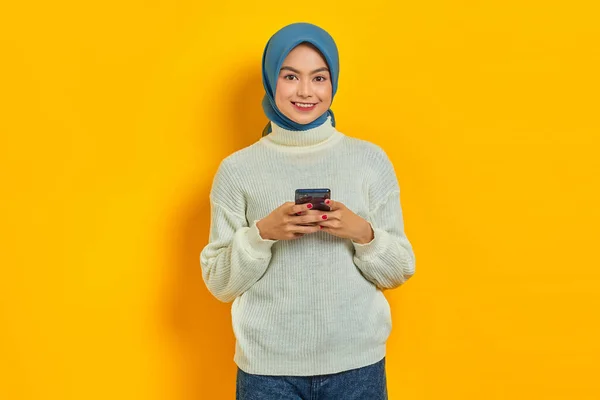 Веселая Молодая Азиатка Белом Свитере Хиджабе Использующая Мобильный Телефон Смотрящая — стоковое фото