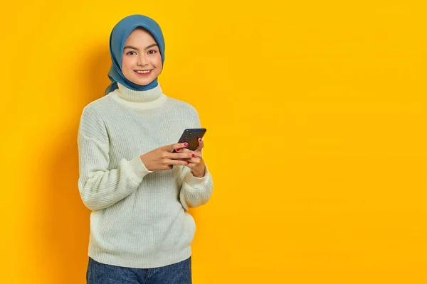 Веселая Молодая Азиатка Белом Свитере Хиджабе Использующая Мобильный Телефон Смотрящая — стоковое фото