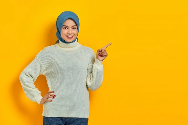 美しいですアジアの女性でホワイトセーター指して指脇にコピースペース孤立上の黄色の背景 — ストック写真