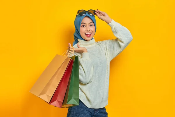 스웨터를 배경에 떨어진 쇼핑백을 쾌활하고 아름다운 아시아 — 스톡 사진
