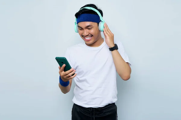 헤드폰을 음악을 파란색 머리띠를 스포츠용 티셔츠를 아시아 스포츠 배경에서 전화를 — 스톡 사진
