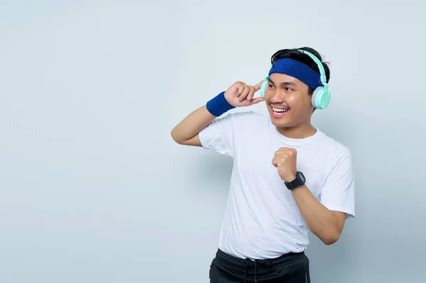 파란색 머리띠와 티셔츠를 아시아 스포츠 트레이너 배경에 헤드폰을 음악을 들으면서 — 스톡 사진