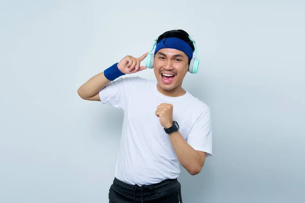 파란색 머리띠와 티셔츠를 아시아 스포츠 트레이너 배경에 헤드폰을 음악을 들으면서 — 스톡 사진