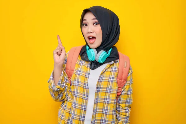 Улыбающаяся Молодая Азиатка Мусульманка Клетчатой Рубашке Наушниками Рюкзаком Указывающая Пальцем — стоковое фото