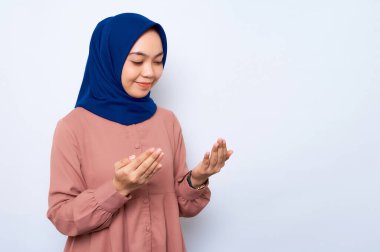 Asyalı Müslüman bir kadının beyaz arka planda izole edilmiş, kolları açık dua eden portresi. İnsanlar dini yaşam tarzı konsepti