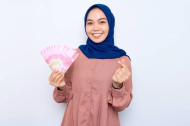 Pembe gömlekli gülümseyen Asyalı müslüman kadın elinde para banknotları tutuyordu ve iki parmağı çapraz olan Koreli kalbi beyaz arka planda gösteriyordu. İnsanlar dini yaşam tarzı konsepti