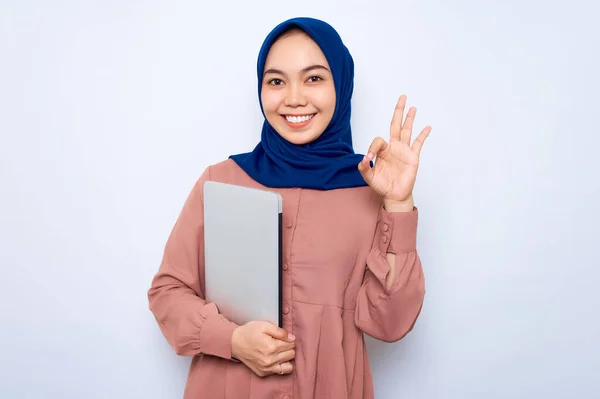 Wesoła Młoda Azjatycka Muzułmanka Różowej Koszuli Trzymająca Laptopa Gestykulująca Dobrze — Zdjęcie stockowe
