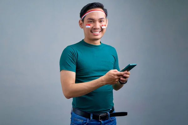 Smiling Young Asian Man Standing Using Mobile Phone Isolated Grey — Stok fotoğraf