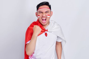 Young Asian man clenched both fist to celebrate Indonesia independence day on August 17, looking at camera with confident and excited expression isolated on white background