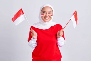 Smiling young Asian muslim woman in red white t-shirt holding flag indonesian to celebrating indonesian independence day on 17 august isolated on white background