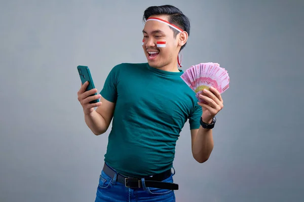 Cheerful Young Asian Man Casual Shirt Holding Mobile Phone Money — Stok fotoğraf