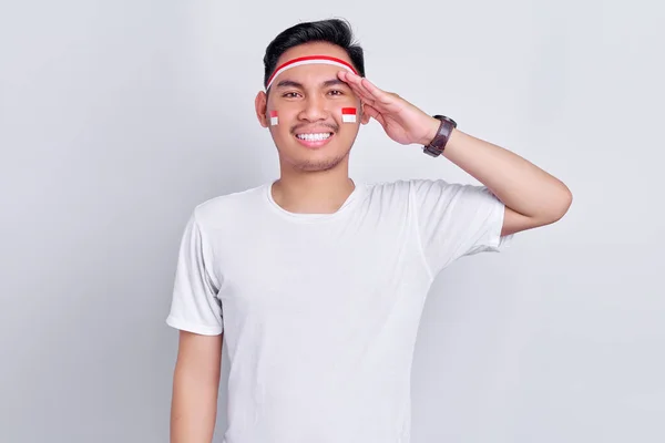 Portrait of smiling young Asian man showing respect gesture while celebrating indonesian independence day on 17 august isolated on white background