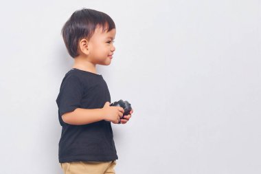 Cheerful child kid boy 2 years wearing black t-shirt play pc game with joystick console isolated on white background