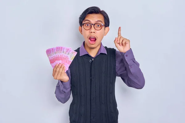年轻英俊的亚洲男子穿着衬衫 手里拿着印着印着卢比钞票的现金 手指被白色背景隔开 吓得魂飞魄散 人的生活方式概念 — 图库照片
