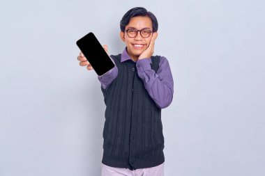 Sıradan gömlekli ve yelekli gülümseyen Asyalı genç beyaz arka planda izole edilmiş mobil uygulama öneriyor. Halk yaşam tarzı konsepti