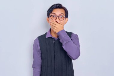 Sıradan gömlekli, ağzı kapalı ve elleri beyaz arka planda olan genç Asyalı şoka uğramış bir adam. Halk yaşam tarzı konsepti