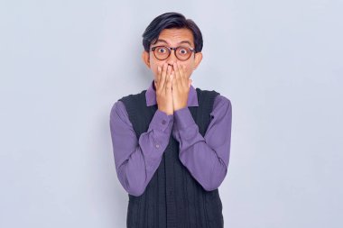Şok olmuş genç Asyalı adam beyaz arka planda izole edilmiş bir hata yüzünden ağzını eliyle kapatıyor. Halk yaşam tarzı konsepti
