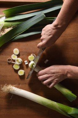 Bir aşçının ahşap bir pırasa keserken yüksek açılı görüntüsü