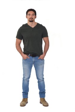 Bir adamın elini cebine sokup beyaz arka plandaki kameraya bakması.