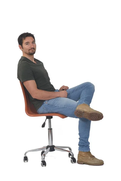 カメラを見て脚を白い背景に交差する椅子に座っている男の完全な肖像画の側面図 — ストック写真