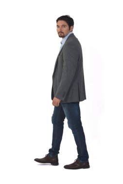 Ceketli bir adamın beyaz arka planda yürüyen kameraya bakışını.