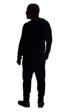 Sıradan kıyafetler giyen bir adamın siluetinin arka görünüşü başka yöne bakıyor.