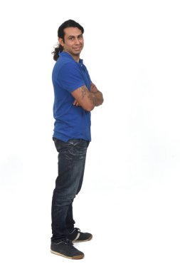 Beyaz arka planda kamera ve kollara bakan at kuyruklu ve dövmeli bir adamın yan görüntüsü.