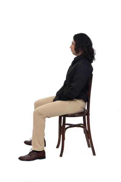 白い背景の上に椅子に座っているシャツや靴やパンツを着た男の側面図 — ストック写真