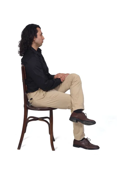 白い背景の上に椅子や脚の上に座っているシャツや靴やパンツを着た男の横顔 — ストック写真