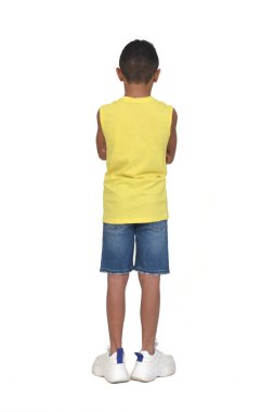 Şort giymiş ve kolsuz beyaz arka planda kollarını kavuşturmuş bir çocuğun tam portresi.