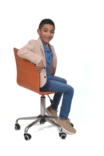 Widok Boku Chłopca Siedzi Krzesło Obrócone Patrząc Aparat Fotograficzny Białym — Zdjęcie stockowe