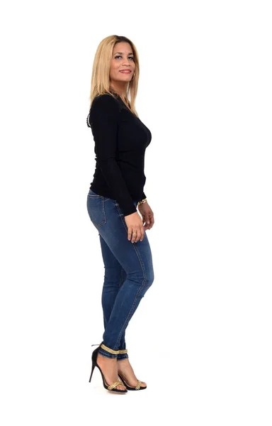 白い背景にジーンズとヒールの靴を履いたカメラを見て歩く女性の横顔の肖像画 — ストック写真