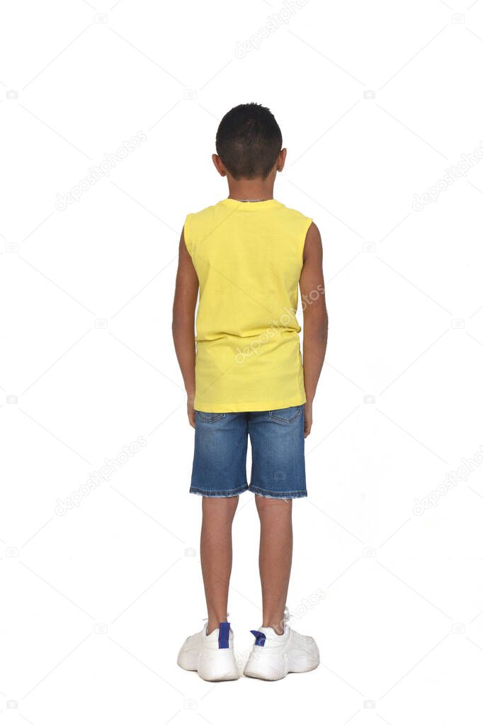 rear view of full portrait of a boy dressed in shorts and sleeveless with arms crossed on white background