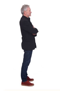 Kotlu spor ayakkabı ve beyaz arka planda kolları çaprazlanmış spor ceket giyen adamın yan görüntüsü.