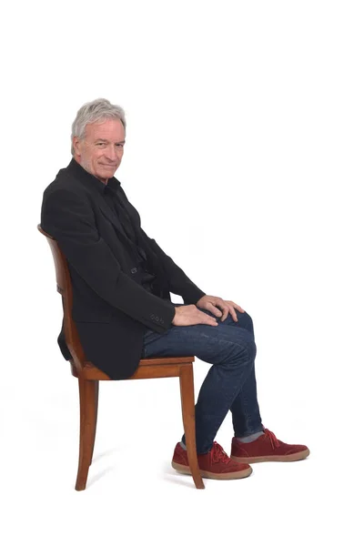 Vista Lateral Homem Sentado Cadeira Com Sapatilhas Jeans Blazer Olhando — Fotografia de Stock