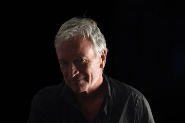 Siyah arka plandaki yaşlı bir adamın vesikalık fotoğrafı.