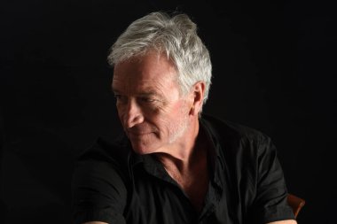 head shit of a  senior man looking away  on black background