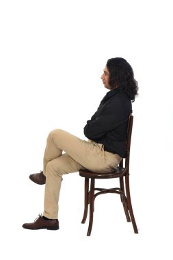 Gömleği, ayakkabısı ve pantolonu olan bir adamın yan görünüşü sandalyede, bacakları ve kolları beyaz arka planda kesişiyor.