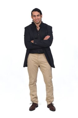 Gömleği, ayakkabıları ve ceketi beyaz arka planda çapraz duran gülümseyen bir adamın ön görüntüsü.