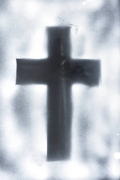 drawing of a cross with spray paint on black paper background