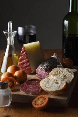  view of a  typical spanish food,tomato,wine,bread, cheese, sausage and olive oil on a wooden table