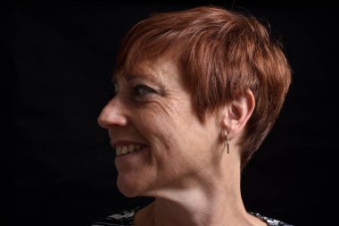 portriat of a middle-aged woman looking away on black background