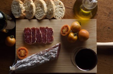close up of a spanish food,tomato,wine,bread, sausage and olive oil on a wooden table