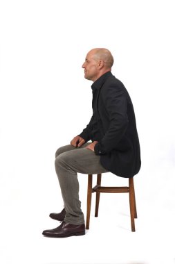side view of a full portrait of a man sitting on chair with cross-legged on white background