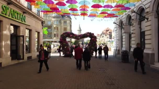 Timisoara Romania 2019年4月19日 ティムフラリス国際フラワーフェスティバルの通りに吊るされたカラーの傘 ルーマニアのティミソアラでストリートアートの花祭りを楽しむ人々 — ストック動画