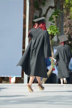 Üniversite mezunu öğrenciler parkta fotoğraf çekimi yapıyorlar.