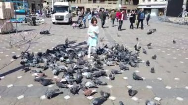 TIMISOARA, ROMANIA - 19 Nisan 2019: çocuklar şehir merkezinde güvercinlerle oynuyorlar