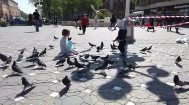 TIMISOARA, ROMANIA - 19 Nisan 2019: çocuklar şehir merkezinde güvercinlerle oynuyorlar