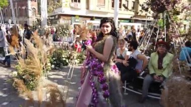 TIMISOARA, ROMANIA - 19 Nisan 2019: Zafer Meydanı, TIMFLORALIS Uluslararası Çiçek Festivali. Festivalin kraliçesi çiçekli bir elbise giyerek sokakta yürüyor..